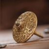 A top-down macro shot of the brass fidget spinner, highlighting the detailed relief carving of the two intertwined celestial dragons.