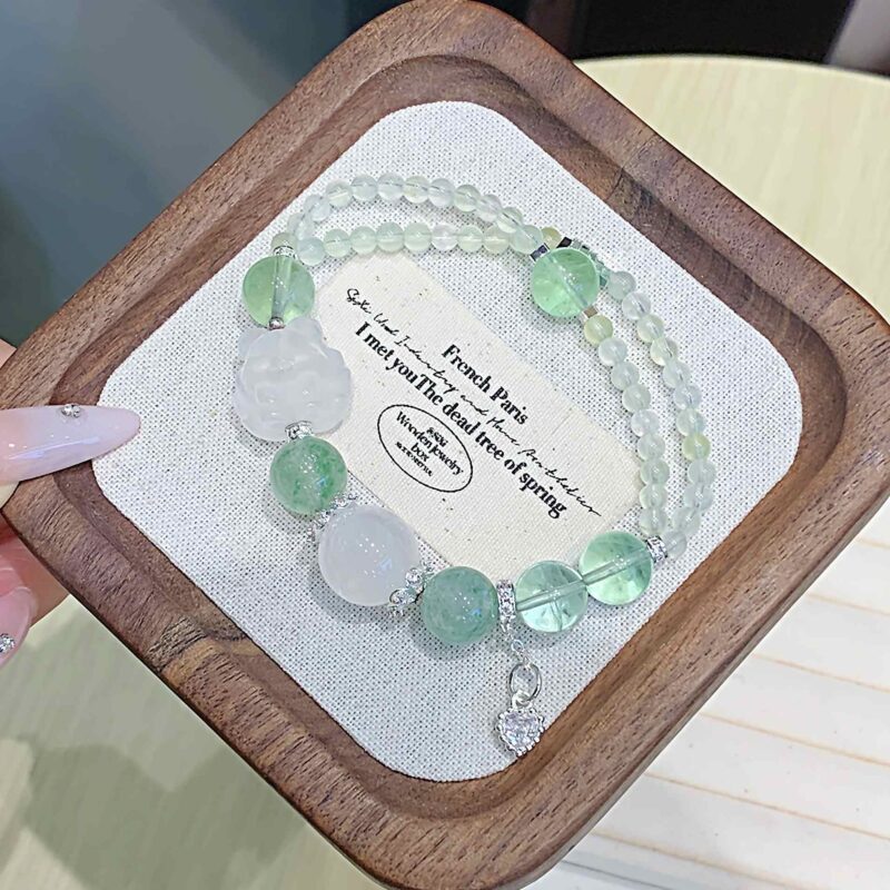 A close-up detail shot of the green rutilated quartz crystal bead on the Chinese Goat Zodiac.