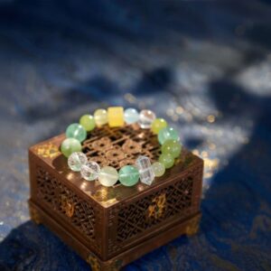 A Chinese Monkey Zodiac crystal bracelet with green rutilated and phantom quartz beads.