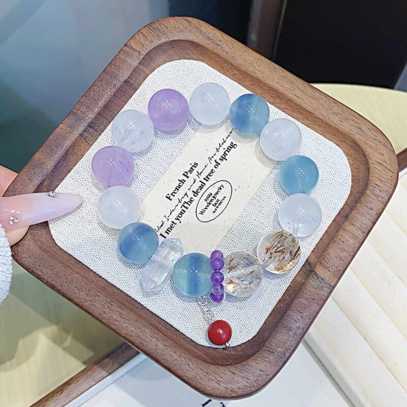 A close-up detail shot of the green rutilated quartz crystal bead on the Chinese Rat Zodiac.