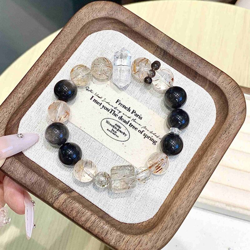 A close-up detail shot of the green rutilated quartz crystal bead on the Chinese Snake Zodiac.