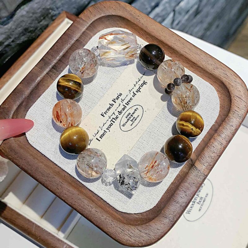 A close-up detail shot of the green rutilated quartz crystal bead on the Chinese Tiger Zodiac.