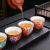 A person enjoying a Gongfu tea ceremony, pouring tea into an exquisite enameled handmade ceramic teacup.