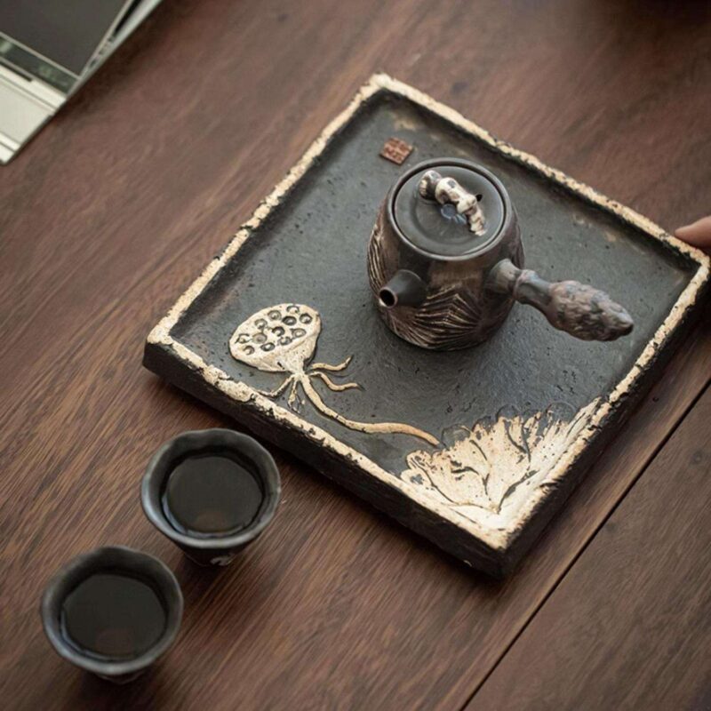 An elegant overhead-handle handmade ceramic teapot with a rustic, dark wabi-sabi glaze, perfect for a traditional Kung Fu tea set.