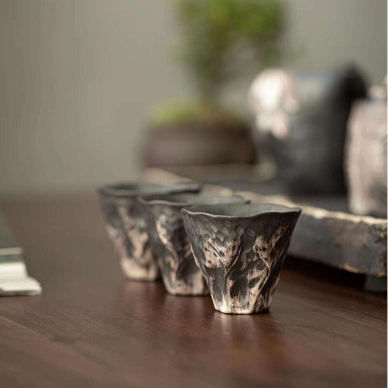 An organically shaped Lotus Leaf ceramic tea tray with a stunning wabi-sabi glaze, used as a coaster in a handmade Kung Fu tea set.