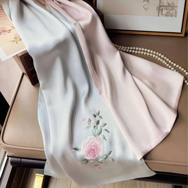 An elegant, open blue Handmade Suzhou Embroidery Silk Gift Box displaying its contents: a hand-embroidered silk scarf, an ebony hairpin, a pearl necklace, and an enamel brooch.