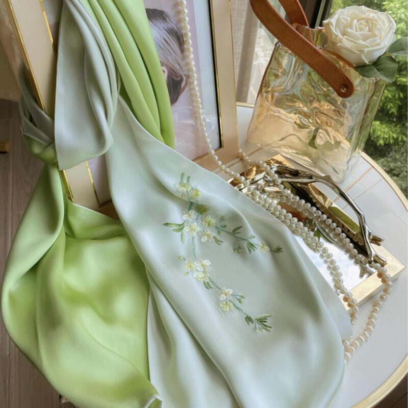 An elegant, open green Handmade Suzhou Embroidery Silk Gift Box displaying its contents: a hand-embroidered silk scarf, an ebony hairpin, a pearl necklace, and an enamel brooch.