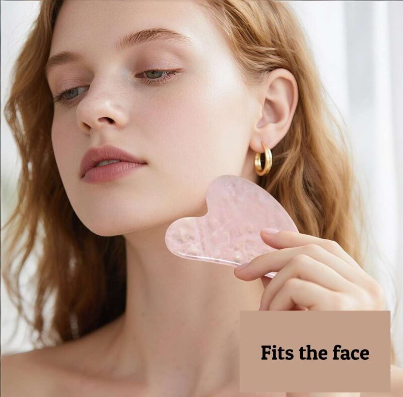A model demonstrates how to use a jade gua sha facial tool on her face.
