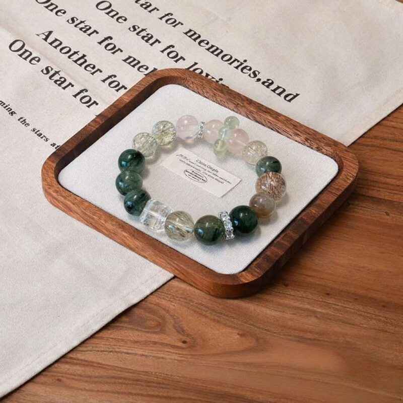 A close-up detail shot of the green rutilated quartz crystal bead on the Jia Wood bracelet.