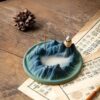 The artisanal backflow incense burner in a mountain style shown without smoke, highlighting its detailed ceramic craftsmanship and serene blue-green glaze.