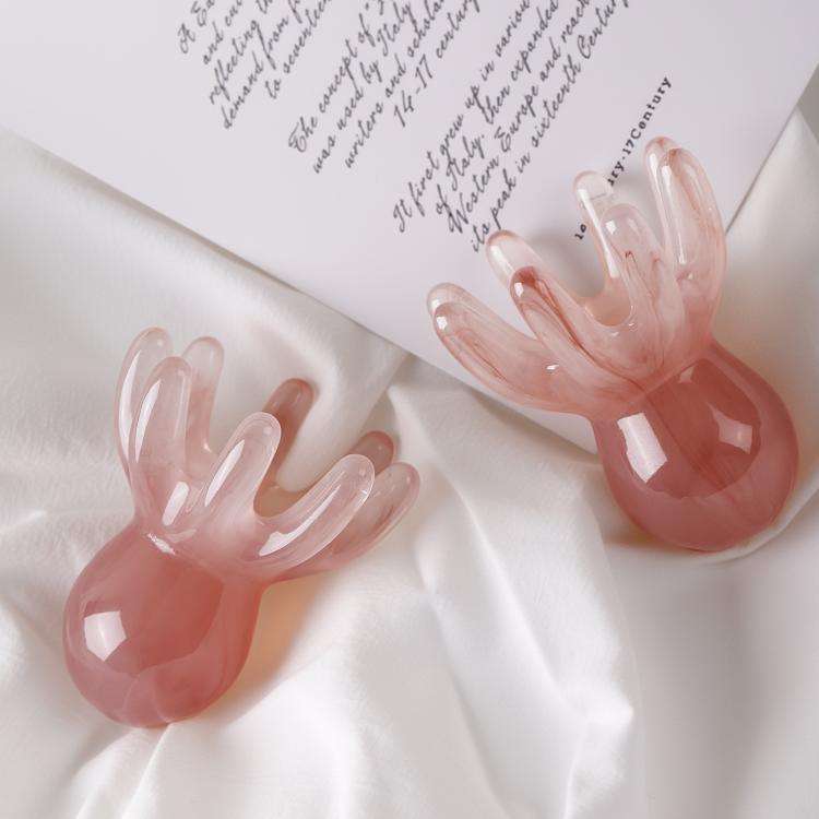 A beautiful pink marbled resin octopushead massage tool on the desk.