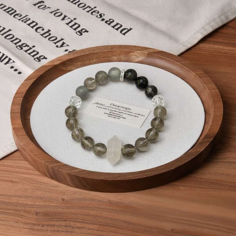 A close-up detail shot of the green rutilated quartz crystal bead on the Ren Water bracelet.