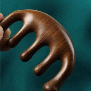 An elegant, dark green sandalwood scalp massager comb with wide, rounded teeth, resting on a clean, neutral background.