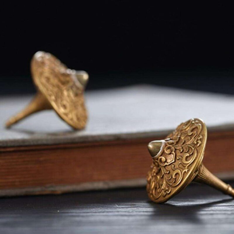 The elegant brass fidget spinner resting on a modern executive desk next to a leather-bound book, serving as a sophisticated focus tool.