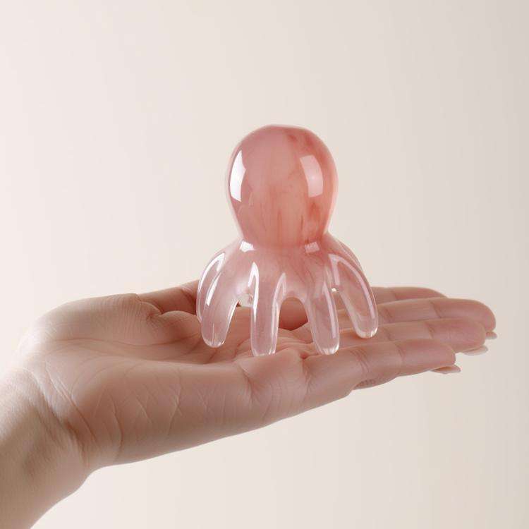 A person relaxing with their eyes closed while using the pink octopus massage comb to gently massage their scalp.