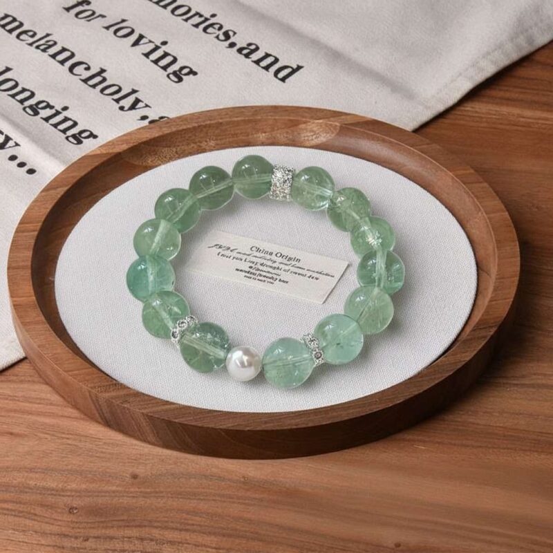 A close-up detail shot of the green rutilated quartz crystal bead on the Yi Wood bracelet.