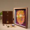 Elegant 3D Chinese Paper Cutting Fenghuang shadow box displayed on a rustic wooden stand, representing harmony and rebirth in Feng Shui decor.