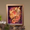 Woman holding a framed 3D Chinese Paper Cutting Vermilion Bird artwork, showing the colorful Phoenix facing the sun against a walnut wood frame.