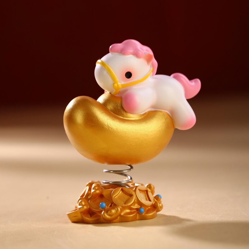 Close up of the Instant Wealth Year of the Horse Creative Spring Ornament with pink hair holding a gold ingot, mounted on a coin base with a spring.