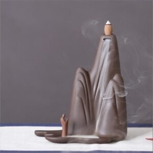 Ceramic Backflow Incense Burner Mountains and Water style standing next to its beige packaging box, showing the mountain shape and small figure.
