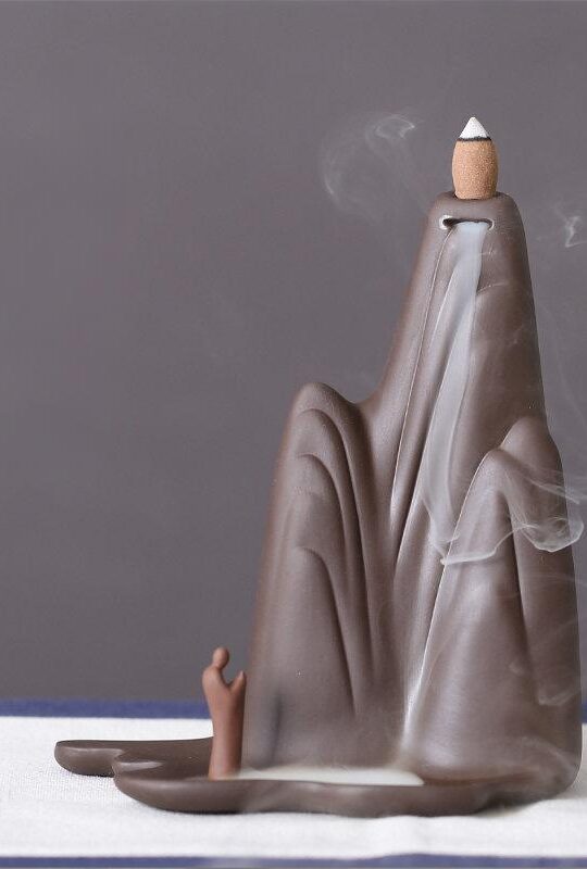 Ceramic Backflow Incense Burner Mountains and Water style standing next to its beige packaging box, showing the mountain shape and small figure.