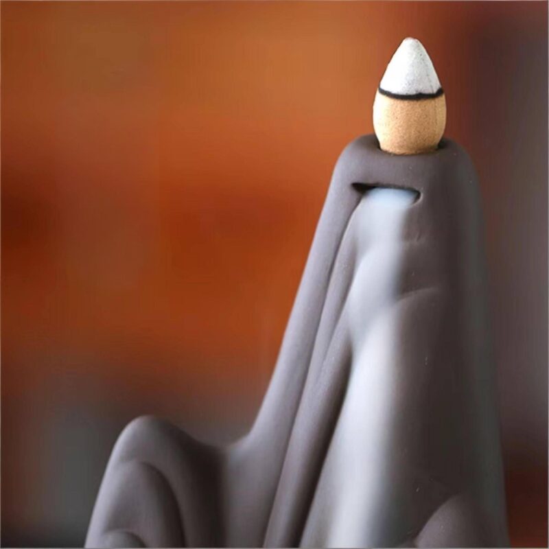 Dramatic smoke waterfall cascading down the cliff face of the Backflow Incense Burner Mountains and Water, creating a Zen mist effect.