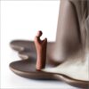 Close up of the small figure observing the smoke waterfall on the Backflow Incense Burner Mountains and Water, set against a blurred wooden background.