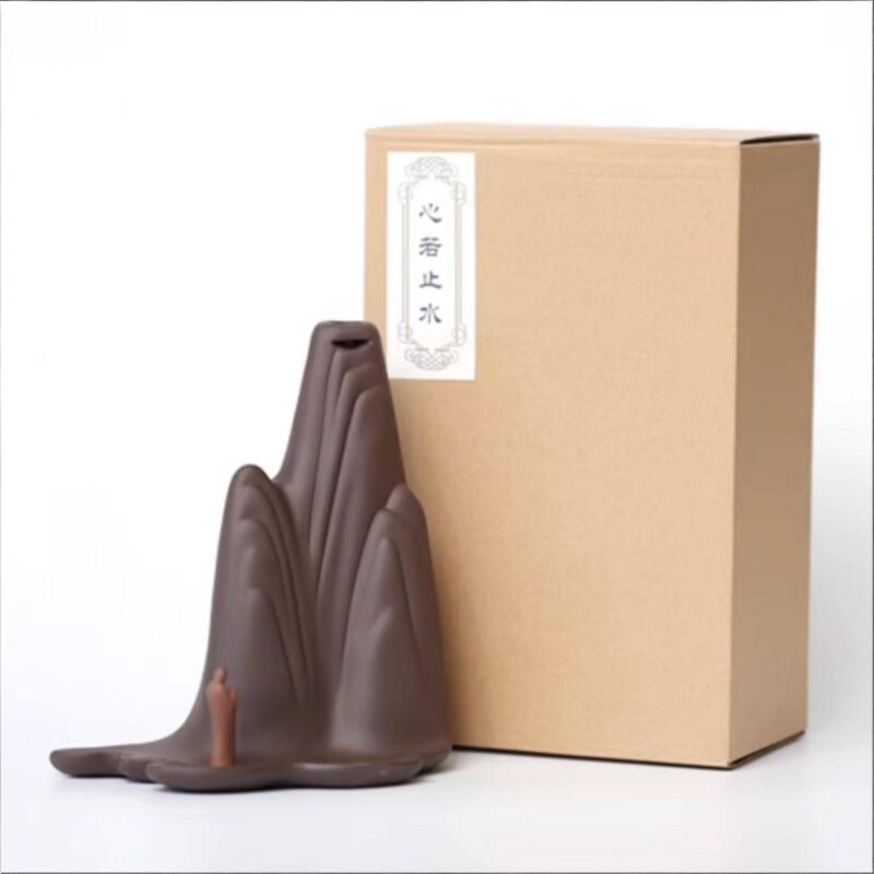 Close up of the small figure observing the smoke waterfall on the Backflow Incense Burner Mountains and Water, set against a blurred wooden background.