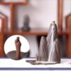 Close up of the small figure observing the smoke waterfall on the Backflow Incense Burner Mountains and Water, set against a blurred wooden background.