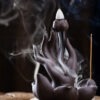 Close up of the smoke waterfall effect flowing down the Buddha hand backflow incense burner from a lit cone.