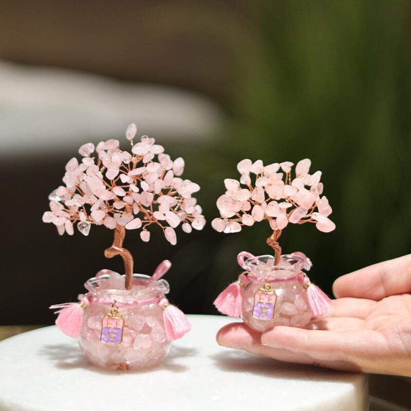 Detail shot of the glass pot base of a Feng Shui Crystal Tree filled with purple crystal chips and adorned with a lucky wealth charm.