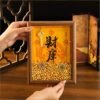 Hands holding a Walnut-colored Feng Shui Wealth Opening Frame, showing the depth of the shadow box and the abundance of gold yuanbao inside.