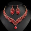 Ruby red Luxury Crystal Glass Party Jewelry Set featuring a V-shaped teardrop rhinestone necklace and matching dangle earrings on a black display.