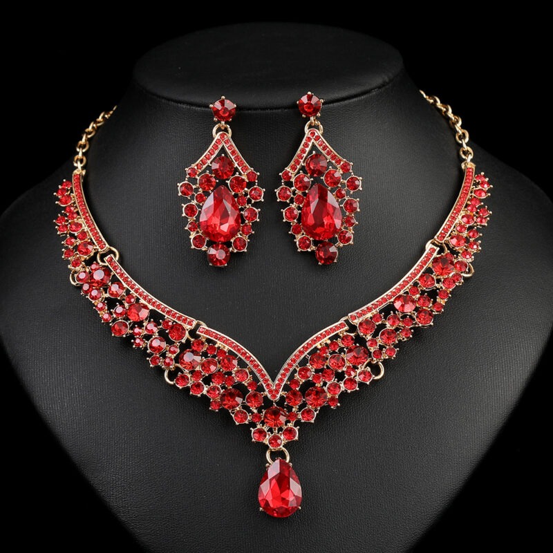 Ruby red Luxury Crystal Glass Party Jewelry Set featuring a V-shaped teardrop rhinestone necklace and matching dangle earrings on a black display.