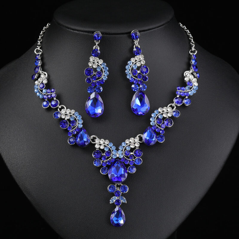 Sapphire blue Luxury Crystal Glass Party Jewelry Set featuring a V-shaped teardrop rhinestone necklace and matching dangle earrings on a black display bust.